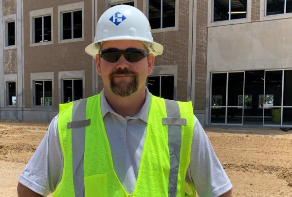 澳门足彩app's Superintendent Sonny Carter posing on a job site wearing a hard hat 和 safety vest.