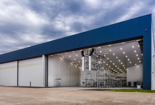 Exterior of MAAS 航空 Painting Facility. Hangar door open showing inside of painting facility.