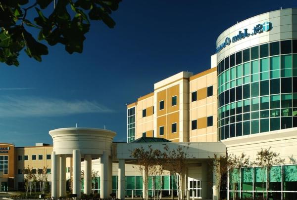 Exterior photo of 奥瓦索医院和医疗办公大楼. Four-story hospital entrance against bright blue skies.