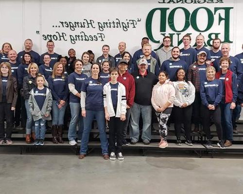 A large group of Benham team members gather for a photo as they volunteer at the Regional Food Bank of Oklahoma