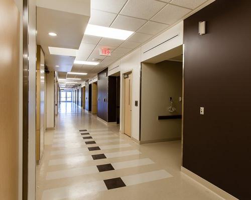 加州质子癌治疗中心走廊的内部照片. Brown and white walls line the hallway.