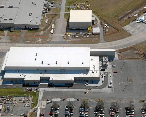 Aerial view of Gulfstream Paint Hangar. 白色建筑周围有车辆停车场，停机坪上停着飞机.