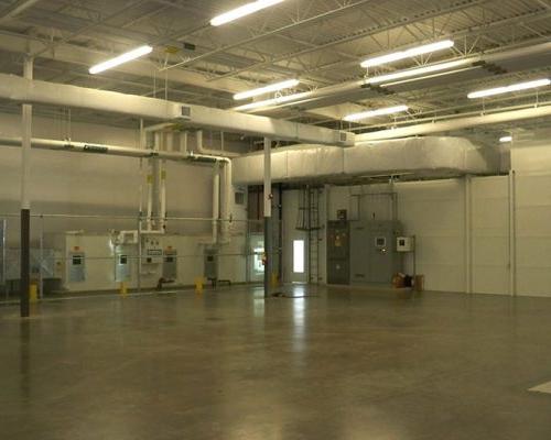 Interior of Gulfstream Paint Hangar. 宽敞的空房间，白色墙壁，混凝土地板，暖通空调和排气管道和荧光灯照明.