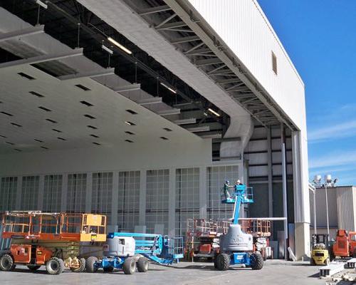 Exterior of Gulfstream Paint Hangar under construction. Large white building and blue sky.